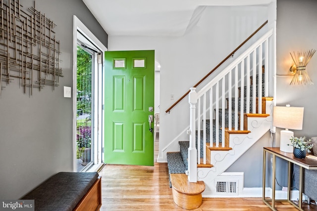 entryway featuring visible vents, baseboards, wood finished floors, and stairway