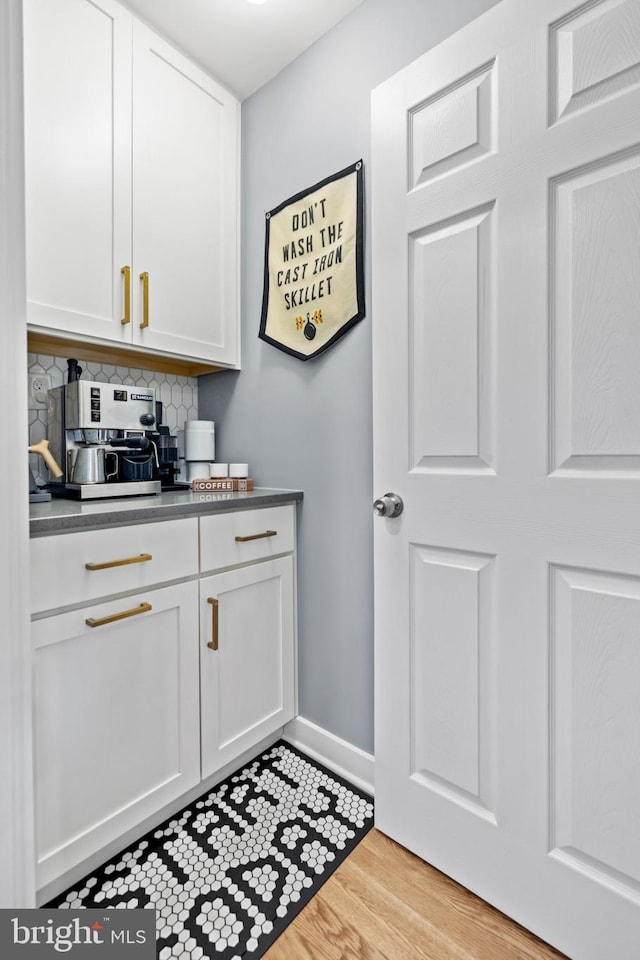 bar featuring backsplash, light wood-type flooring, and baseboards