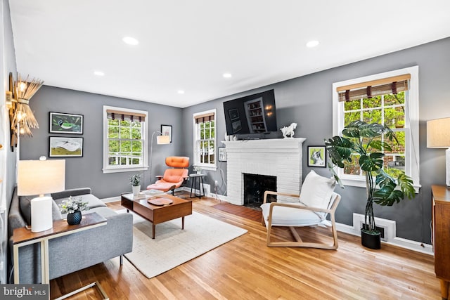 living room with visible vents, baseboards, recessed lighting, a fireplace, and wood finished floors