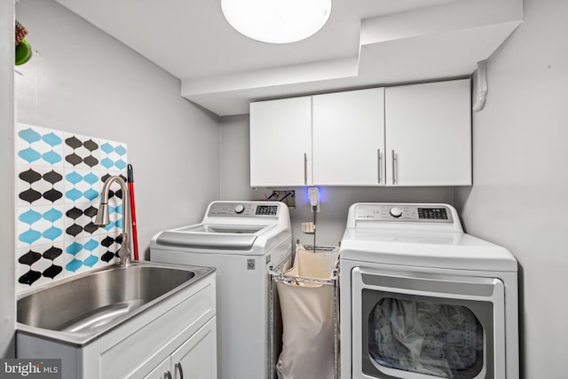 washroom featuring washing machine and clothes dryer, cabinet space, and a sink