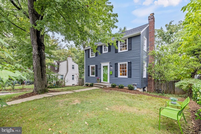 colonial home with a front lawn, fence, and a chimney