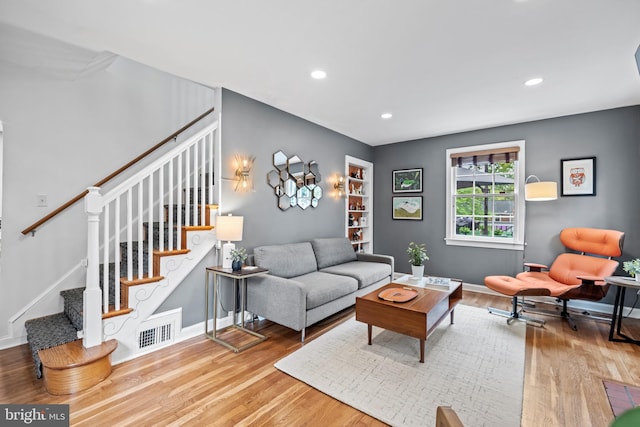 living area featuring stairway, wood finished floors, visible vents, and baseboards