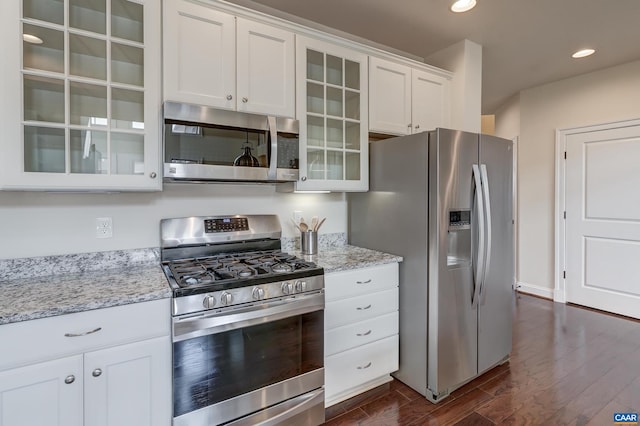 kitchen featuring dark wood-style floors, recessed lighting, stainless steel appliances, glass insert cabinets, and white cabinetry