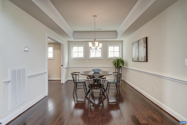 dining space with visible vents, a tray ceiling, dark wood-type flooring, crown molding, and a notable chandelier