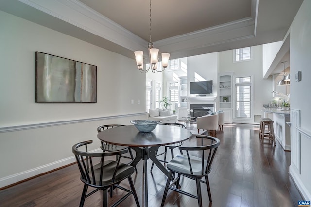 dining room featuring baseboards, dark wood finished floors, ornamental molding, a raised ceiling, and a notable chandelier