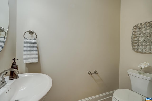 bathroom featuring a sink, baseboards, and toilet