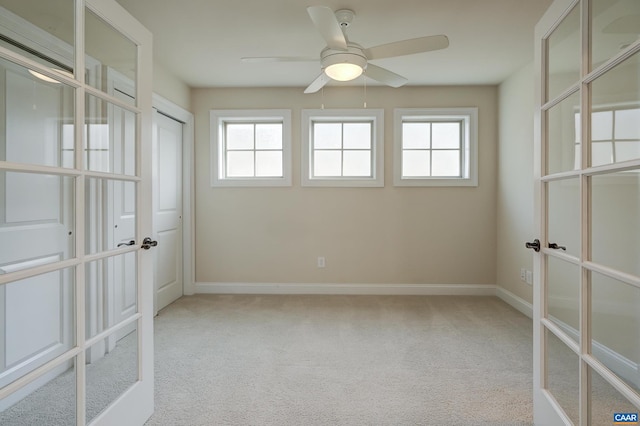 carpeted spare room featuring a wealth of natural light, french doors, and baseboards