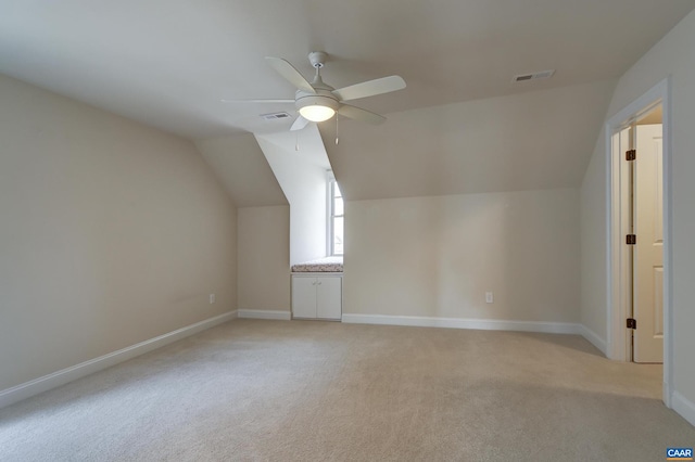 additional living space with visible vents, baseboards, light colored carpet, and a ceiling fan