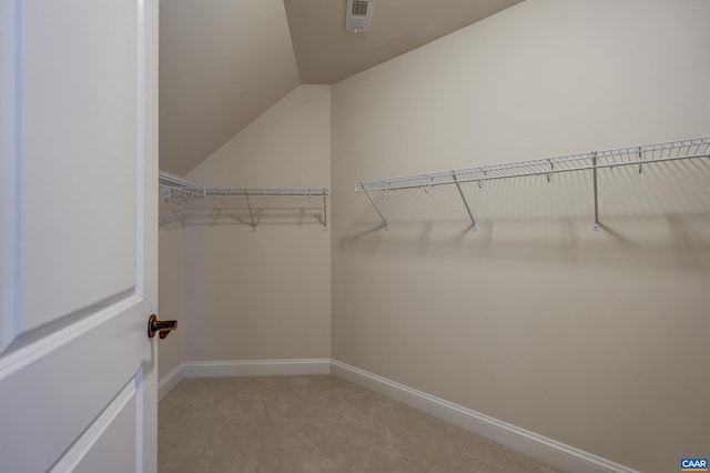 spacious closet with visible vents, light carpet, and vaulted ceiling