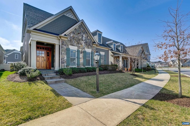 view of front of property with a residential view, a front yard, and stone siding