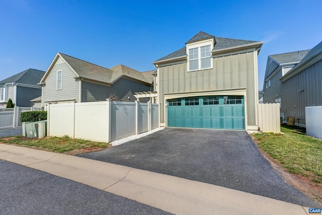 view of front of property featuring aphalt driveway, fence, board and batten siding, and a shingled roof