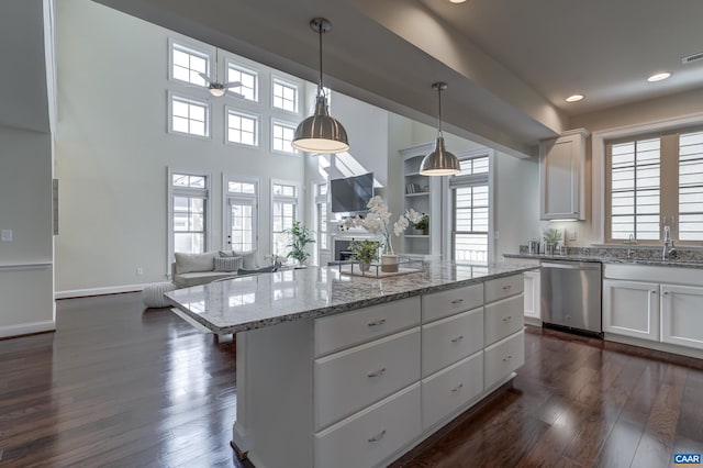 kitchen featuring a kitchen island, stainless steel dishwasher, dark wood finished floors, and white cabinets