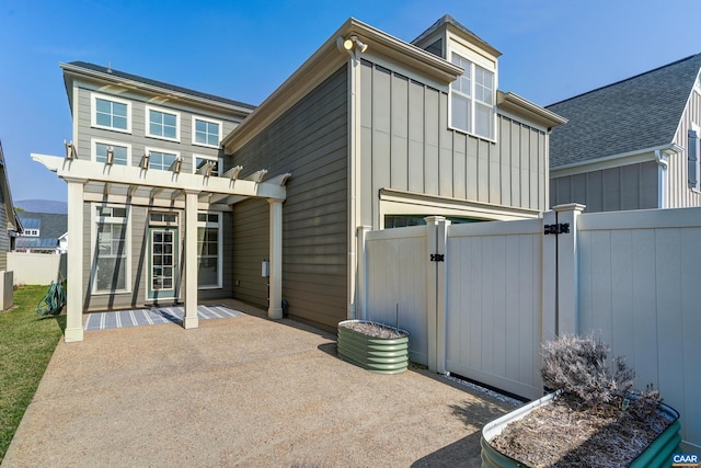 back of house with a gate, board and batten siding, a patio, and fence