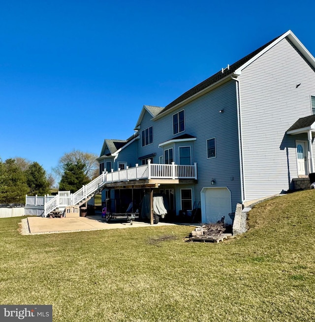 rear view of house featuring a wooden deck, stairway, a lawn, a patio area, and an attached garage