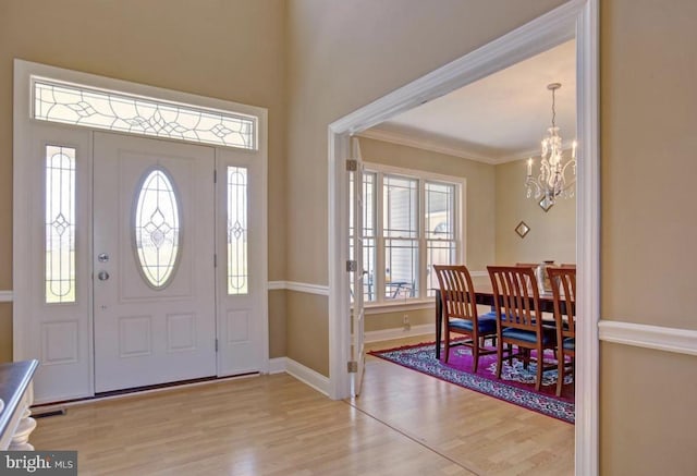 entryway with crown molding, wood finished floors, an inviting chandelier, and baseboards