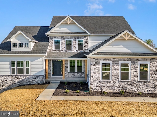 craftsman inspired home featuring a porch, stone siding, and roof with shingles