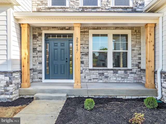 doorway to property featuring covered porch and stone siding