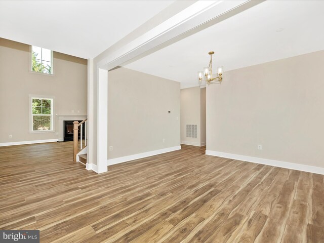 unfurnished living room with baseboards, visible vents, a notable chandelier, and light wood finished floors