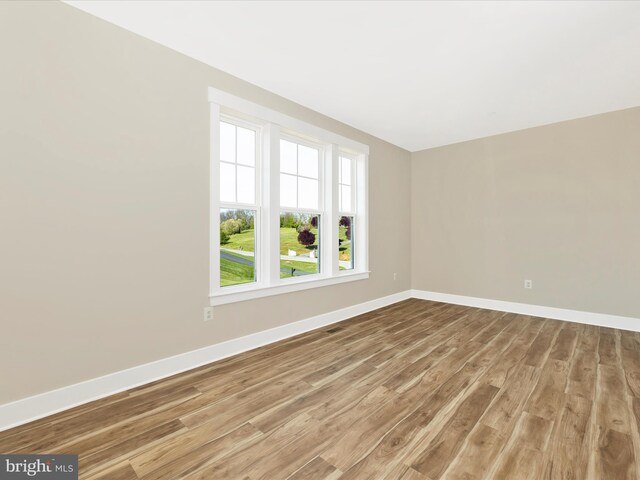 empty room with baseboards and light wood-type flooring