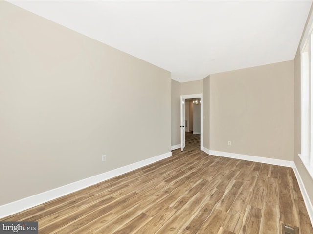 empty room with baseboards, visible vents, and light wood finished floors