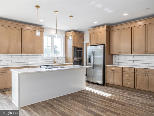 kitchen featuring appliances with stainless steel finishes, wood finished floors, tasteful backsplash, and a center island