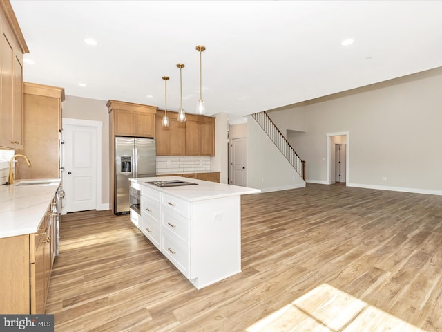 kitchen featuring tasteful backsplash, a sink, a kitchen island, light wood finished floors, and stainless steel refrigerator with ice dispenser