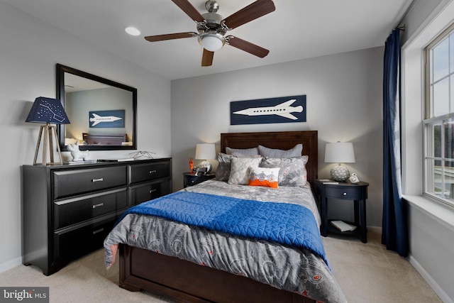 bedroom featuring light colored carpet, a ceiling fan, and baseboards