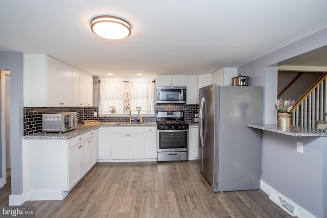 445 Blue Bell Rd, Williamstown, NJ 08094 - kitchen featuring backsplash, white cabinetry, light wood-type flooring, and stainless steel appliances