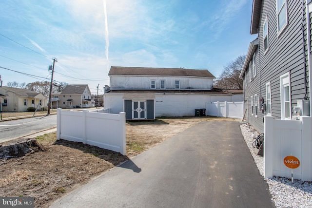 445 Blue Bell Rd, Williamstown, NJ 08094 - view of property exterior featuring an outbuilding, aphalt driveway, a storage shed, fence, and a residential view