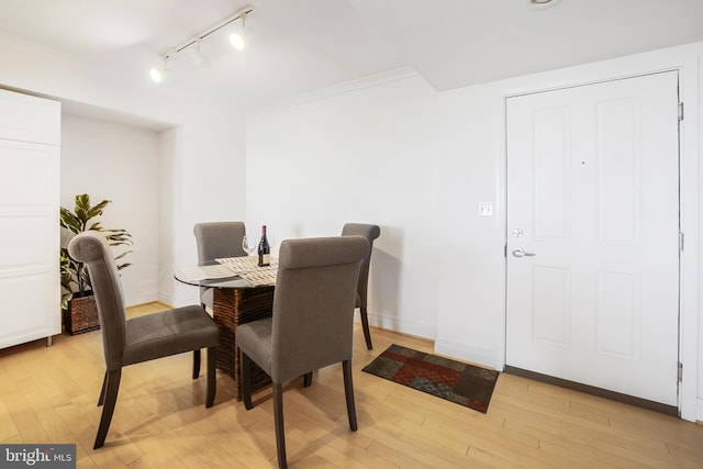 dining area with baseboards, ornamental molding, and light wood finished floors