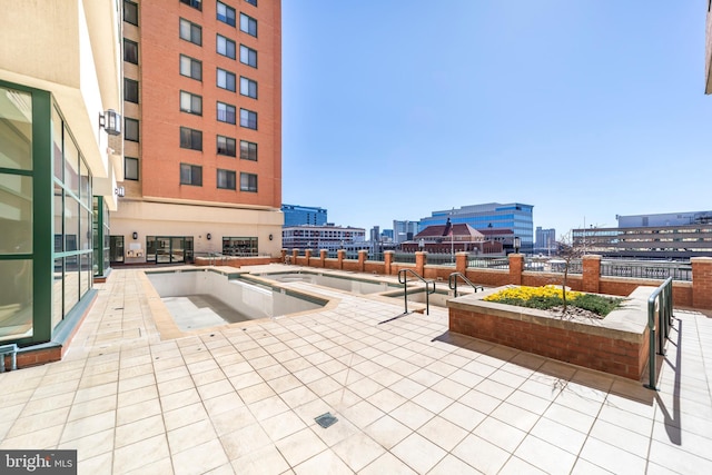 view of pool featuring a jacuzzi, a view of city, and a patio