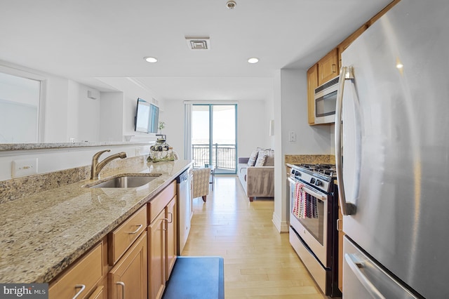 kitchen featuring light wood-type flooring, a sink, visible vents, appliances with stainless steel finishes, and brown cabinets