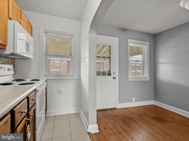 kitchen featuring white appliances, arched walkways, baseboards, and light countertops