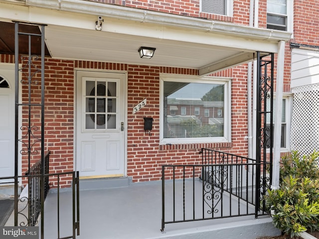 doorway to property featuring brick siding and covered porch