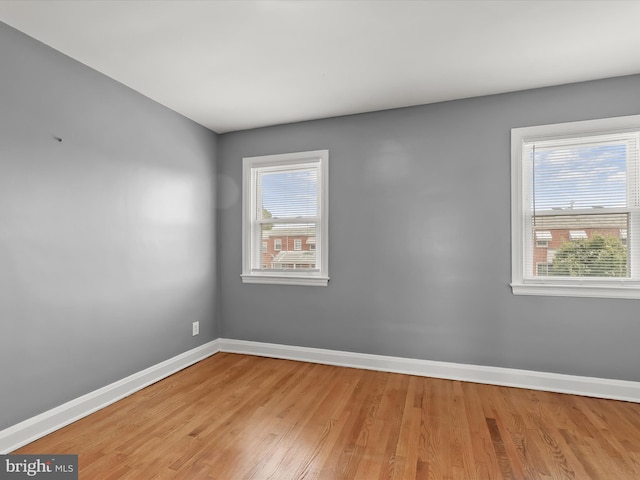 spare room with baseboards and light wood finished floors