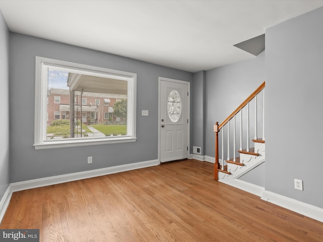 entryway featuring wood finished floors, baseboards, and stairway