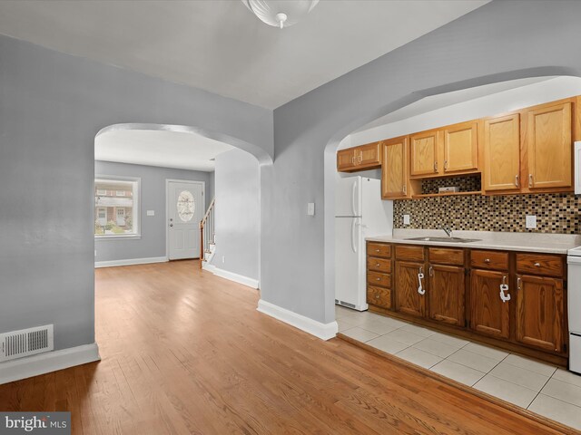kitchen with white appliances, arched walkways, a sink, and light countertops