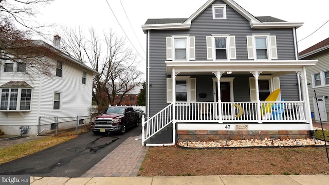 view of front of property featuring aphalt driveway, a porch, and fence