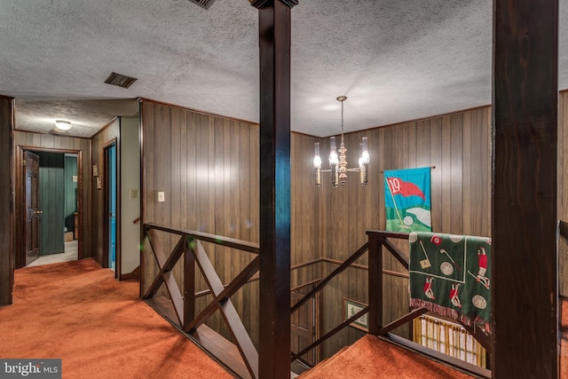 126 Armstrong Pl, Winchester, VA 22602 - staircase featuring visible vents, a textured ceiling, wood walls, carpet flooring, and a chandelier
