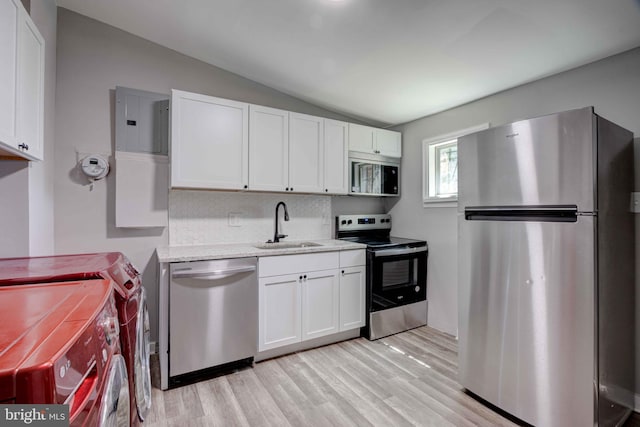 1843 W Pratt St, Baltimore, MD 21223 - kitchen featuring stainless steel appliances, vaulted ceiling, a sink, light wood-style floors, and white cabinetry