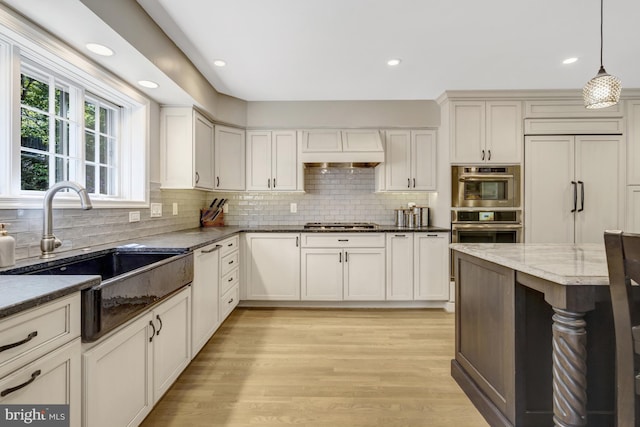 3313 Midland Rd, Fairfax, VA 22031 - kitchen featuring decorative backsplash, custom exhaust hood, a sink, light wood-style flooring, and decorative light fixtures