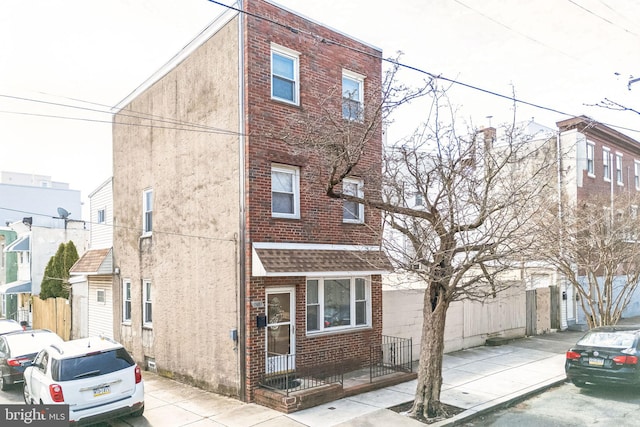 view of front of property with stucco siding, brick siding, and fence