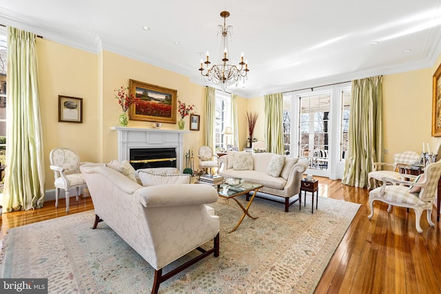 24 Whitfield Rd, Baltimore, MD 21210 - living area featuring a glass covered fireplace, wood-type flooring, an inviting chandelier, crown molding, and baseboards