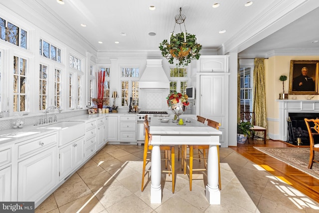 24 Whitfield Rd, Baltimore, MD 21210 - kitchen with gas stove, custom exhaust hood, a sink, white cabinets, and crown molding