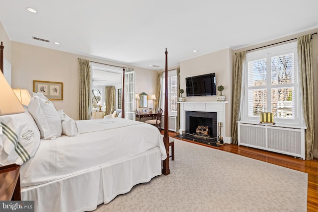 24 Whitfield Rd, Baltimore, MD 21210 - bedroom with multiple windows, a fireplace, wood finished floors, and radiator heating unit