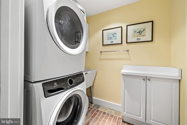 24 Whitfield Rd, Baltimore, MD 21210 - laundry room with stacked washer and dryer, cabinet space, brick floor, and baseboards