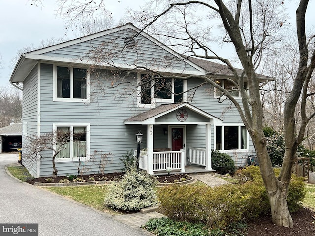 american foursquare style home with a porch and a shingled roof