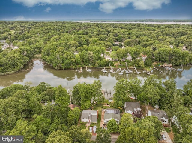 aerial view of property and surrounding area featuring a large body of water and a heavily wooded area