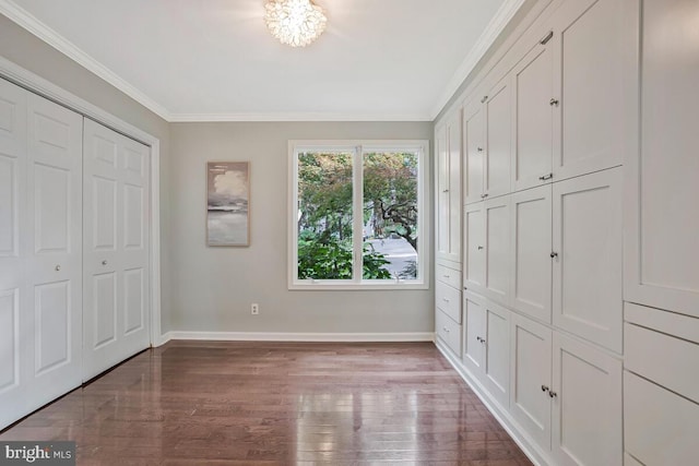 unfurnished bedroom with wood finished floors, baseboards, crown molding, and a closet
