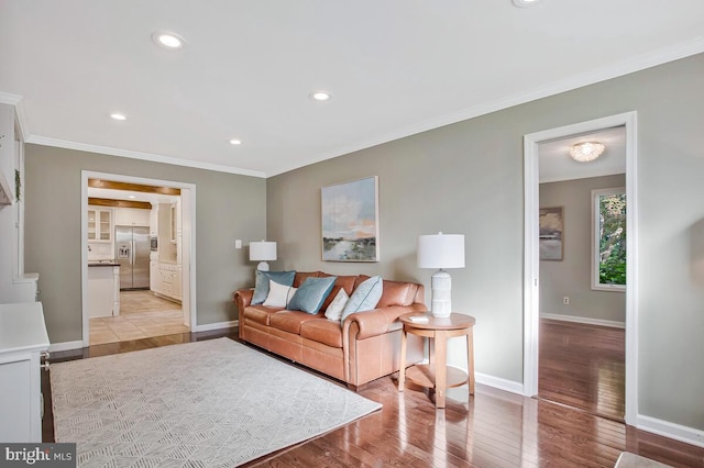 living room with crown molding, baseboards, light wood finished floors, and recessed lighting